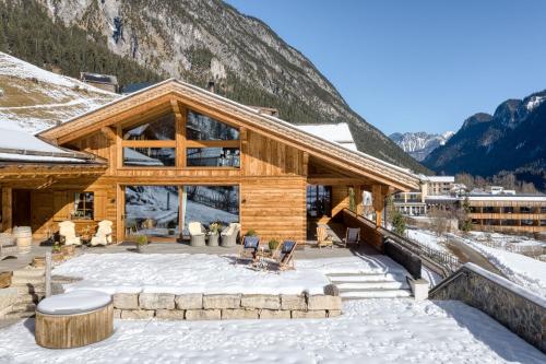 a log cabin in the snow with mountains in the background at Penthouse im Chalet GM by A-Appartments in Gallaverda