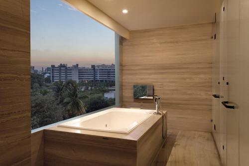 a bath tub in a bathroom with a large window at Sheraton Grand Bengaluru Whitefield Hotel & Convention Center in Bangalore