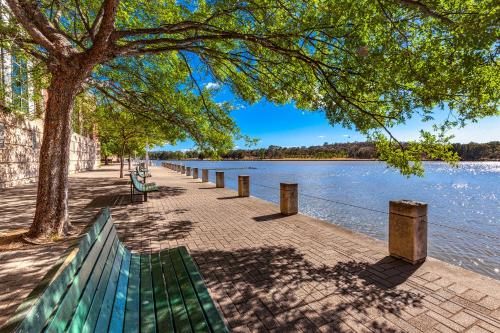 a green park bench next to a lake at Tuggeranong Short Stay #07 - Sleeps 6 in Tuggeranong