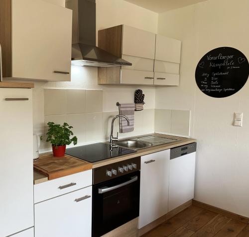 a kitchen with white cabinets and a sink and a stove at Ferienwohnung Drachennest mit Sonnenterrasse in Feldkirch