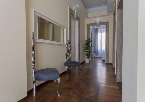 a hallway with two chairs and a mirror at Relais Villa Coppedè in Rome