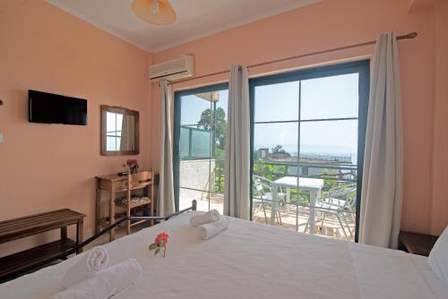 a bedroom with a bed and a large window at Andromaches large apartment 2 in Achílleion