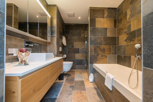 uma casa de banho com uma banheira, um WC e um lavatório. em Montela Hotel & Resort - Suiten em Saas-Grund