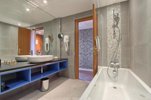 La salle de bains est pourvue de 2 lavabos, d'une baignoire et d'une douche. dans l'établissement Timhotel Opéra Blanche Fontaine, à Paris