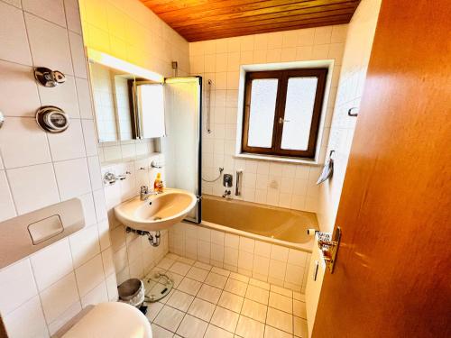 a bathroom with a sink and a toilet and a tub at Ferienwohnung Bergsonne mit Oberstaufen Plus in Oberstaufen