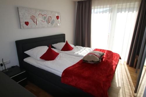 a bed with red pillows and a red blanket on it at FeWo Glockenstüble mit Schwimmbad und Sauna in Oberstaufen