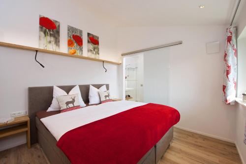 1 dormitorio con 1 cama grande con manta roja en 5 Sterne Ferienwohnung Hochgratblick mit Schwimmbad und Sauna en Oberstaufen