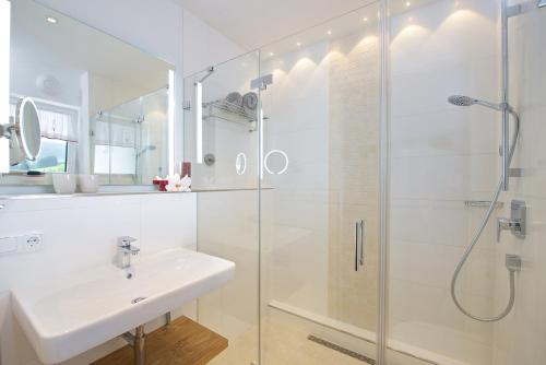 a white bathroom with a sink and a shower at 5 Sterne Ferienwohnung Hochgratblick mit Schwimmbad und Sauna in Oberstaufen