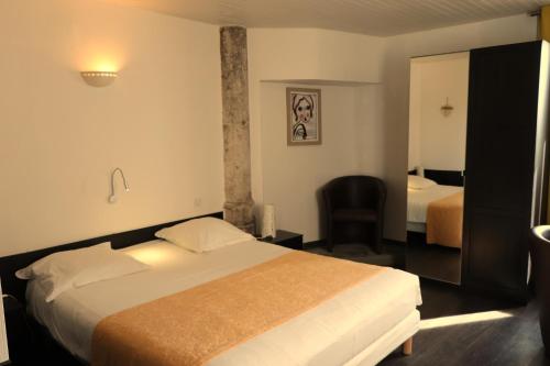 Pokój hotelowy z łóżkiem i krzesłem w obiekcie Hôtel Restaurant LE SAINT AUGUSTIN w mieście Saint-Amour