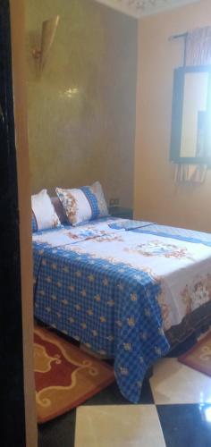 a bedroom with a bed with a blue comforter at Dar LBAHJA 3 in Ouzoud