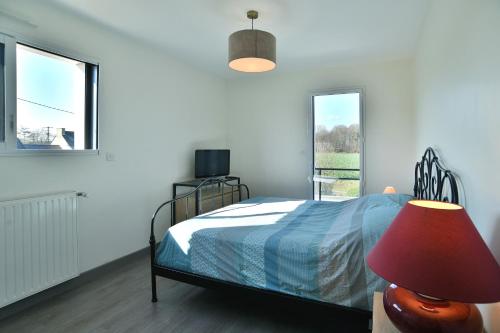 una camera da letto con un letto con una lampada e una finestra di Les Figuiers - Joli maison pour 8 a Plouër-sur-Rance