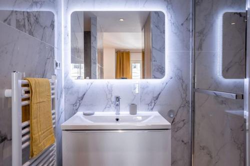 une salle de bain blanche avec un lavabo et un miroir dans l'établissement Luxury Apt With Balcony On Famous Rue D'antibes! - Kiss Apartment by Halldis, à Cannes