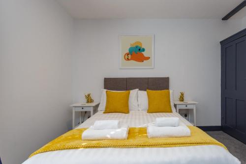 a bedroom with a large bed with yellow pillows at Methuen Mews - 2 double bedroom townhouse within walking distance to beach, on-street parking in Portsmouth in Portsmouth