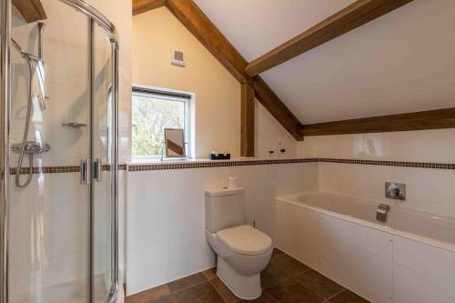 a bathroom with a toilet and a shower and a tub at Otters Holt in Somerford Keynes