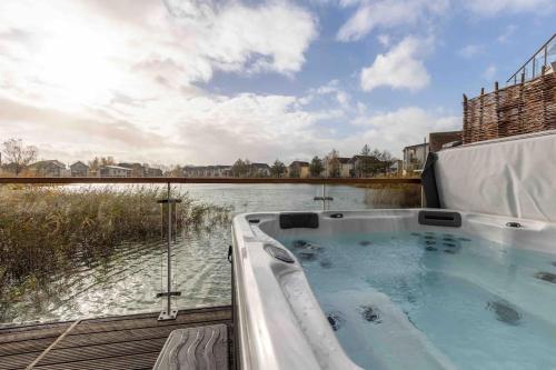a hot tub sitting on the side of a body of water at Otters Holt in Somerford Keynes