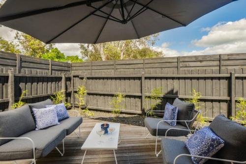 a patio with chairs and an umbrella on a wooden deck at Martini Manor in Capel Sound