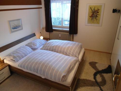 een slaapkamer met een bed met 2 kussens en een raam bij Ferienwohnung Sonnenblick in Oberstaufen