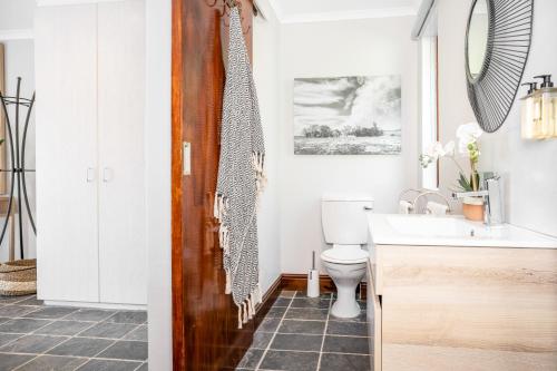 y baño con aseo, lavabo y espejo. en Avemore Time Out - with Backup Power, en Stellenbosch