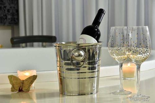 a bottle of wine in a bucket next to two glasses at סוויטות כחול לבן - בקתות וסוויטות מושלמות עם ג'קוזי פרטי ובריכה מחוממת במתחם in Shahar
