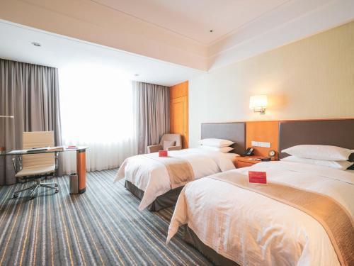 a hotel room with two beds and a desk at Ramada Plaza Shanghai Pudong Airport - 3 mins to PVG depature floor & check entrance with hotel shuttle in Shanghai