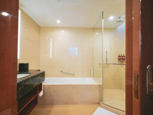 a bathroom with a bath tub and a shower at Ramada Plaza Shanghai Pudong Airport in Shanghai