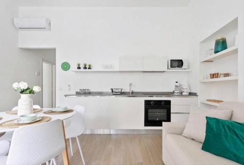 een witte keuken en een woonkamer met een tafel en een bank bij SOFIA LAKE SUITE in Como