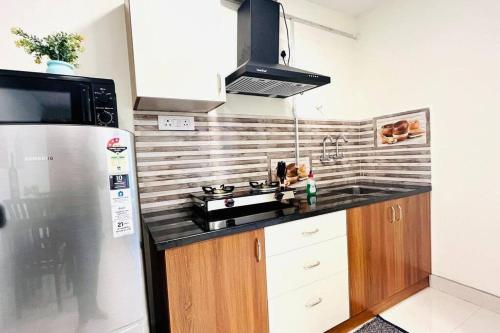 a kitchen with a stove and a refrigerator at BluO Studio Gachibowli - Terrace Garden, Lift in Hyderabad