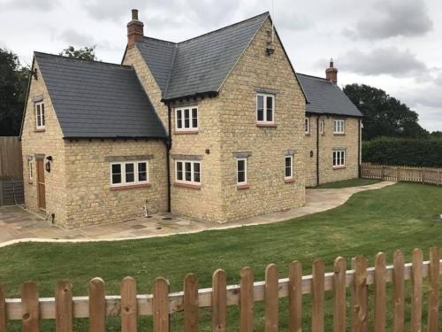 una gran casa de ladrillo con una valla delante de ella en Denbrae, en Brackley