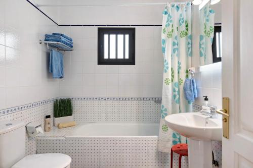 a bathroom with a tub and a toilet and a sink at El Charco Azul in Charco del Palo