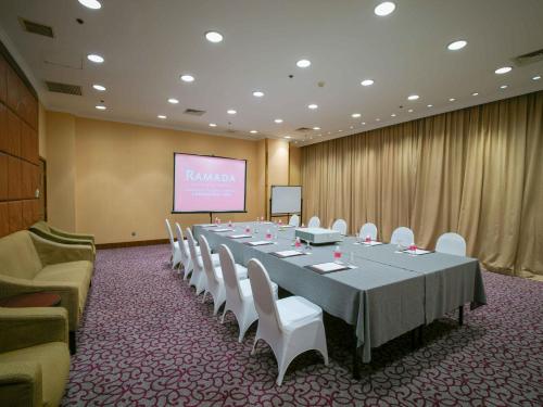 a conference room with a long table and chairs and a screen at Ramada Plaza Shanghai Pudong Airport - 3 mins to PVG depature floor & check entrance with hotel shuttle in Shanghai