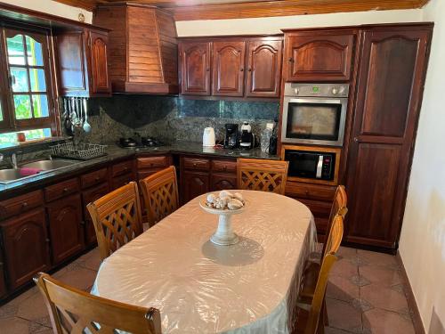 a kitchen with a table and chairs and a kitchen with wooden cabinets at Location saisonniere villa l arosatier in Hell-Bourg