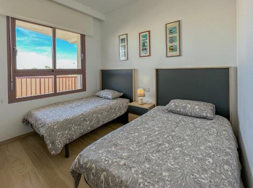 1 dormitorio con 2 camas y ventana en Bianca Beach 222 - Mil Palmeras, vista piscina y mar, en Torre de la Horadada