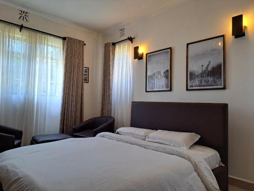 1 dormitorio con 1 cama grande y 2 cuadros en la pared en Enaiteru, en Oyugis