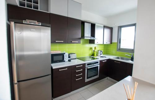 a kitchen with brown cabinets and a stainless steel refrigerator at Glabur Stays - The Amazing 2 BDR - Nicosia City, Free Parking & WiFi in Nicosia