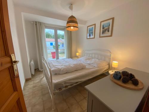 una piccola camera da letto con un letto e una finestra di Les Amourettes - 2 min à pied Plage - Jardin a La Faute-sur-Mer