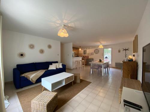 un salon avec un canapé bleu et une table dans l'établissement Les Amourettes - 2 min à pied Plage - Jardin, à La Faute-sur-Mer