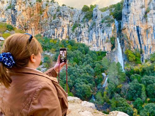 a woman taking a picture of a waterfall at Hotel El Curro in Burunchel