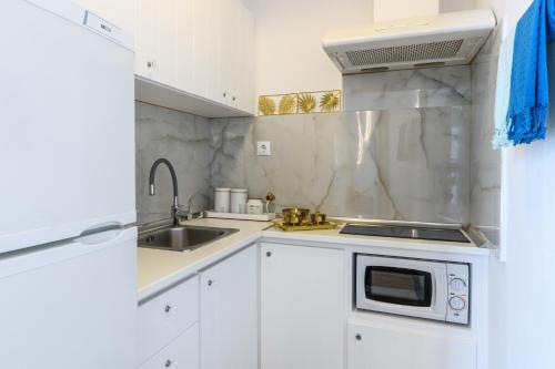 a white kitchen with a sink and a microwave at Seablue Town Maisonette Mykonos in Mýkonos City