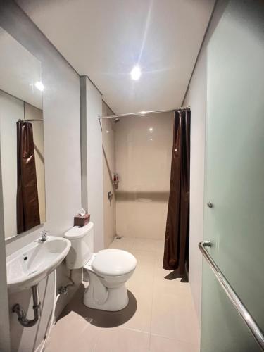 La salle de bains est pourvue de toilettes, d'un lavabo et d'une douche. dans l'établissement Sleep Studio Hotel City Center Surabaya, à Tembok