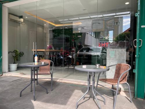 two tables and chairs in front of a store window at Sleep Studio Hotel City Center Surabaya in Tembok