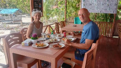a man and woman sitting at a table eating food at Yohana Cottage in Tual