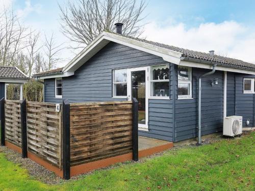 ein blaues Haus mit einem Zaun davor in der Unterkunft 8 person holiday home in Hesselager in Hesselager
