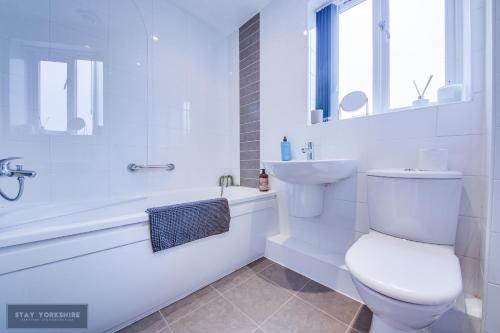 La salle de bains blanche est pourvue de toilettes, d'une baignoire et d'un lavabo. dans l'établissement Stay Yorkshire 1st floor Hamilton Mews Apartment, à Doncaster