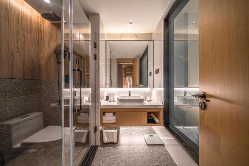ein Bad mit einer Glasdusche und einem Waschbecken in der Unterkunft Ramada Guilin Yangshuo Resort in Yangshuo