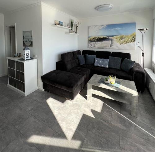ein Wohnzimmer mit einem schwarzen Sofa und einem Tisch in der Unterkunft Haus Seebad Whg 11 in Grömitz