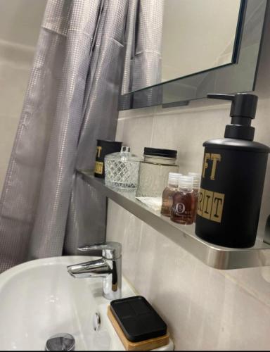 - un lavabo dans la salle de bains avec un distributeur de savon sur une étagère dans l'établissement Studio 23m2 moderne hypercentre - Arènes à 2 min, à Nîmes