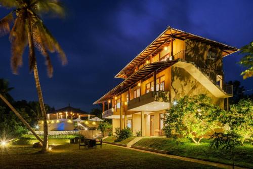 a house with a palm tree at night at Kiss Blossom in Mirissa