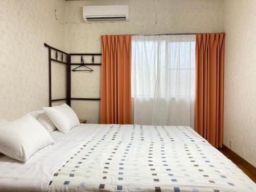 a bedroom with a large bed with an orange curtain at Guesthouse Namaste in Kanazawa