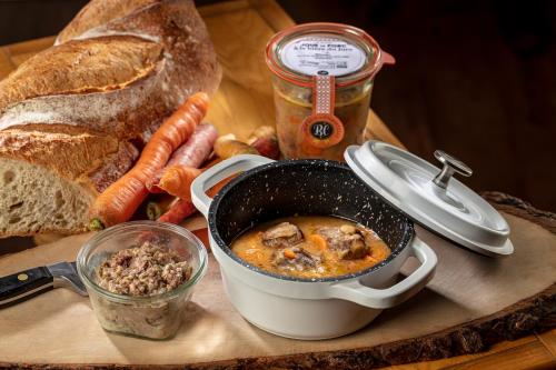 a pot of soup on a cutting board with bread and carrots at Logis Hôtel LBB - les 2 lacs in Clairvaux-les-Lacs