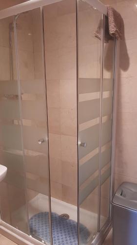 a glass shower in a bathroom with a toilet at TORRE de la FUENTE AprtoVistas Piscina Parking in Oviedo